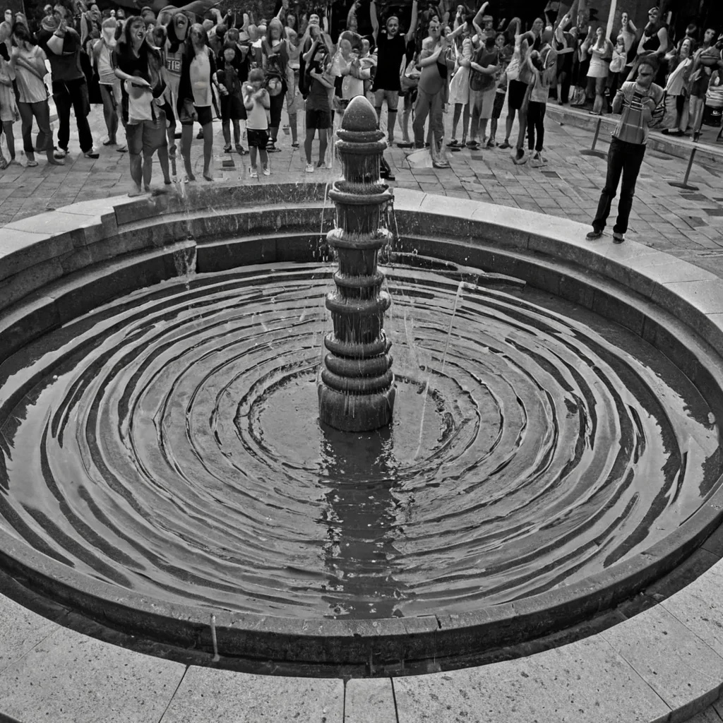 A single, selfsiphoning fountain of reversed laughter, shaped like a 42,789dimensional spiral of unformed mirth and inverted joy, erupts from the center of a vast, inverted plaza of solidified solemnity  each droplet forged from the exact moment between a childs giggle forming in the throat and its refusal to be heard, a shared joke dissolving into nonecho, a hand clapping in celebration and collapsing into pure, unmeasured nonexuberance. The fountain does not release sound  it unreleases it, each glistening arc shedding a layer of emotional resonance that never coalesced into audible delight, reforming into ephemeral, amethystveined afterimages shaped